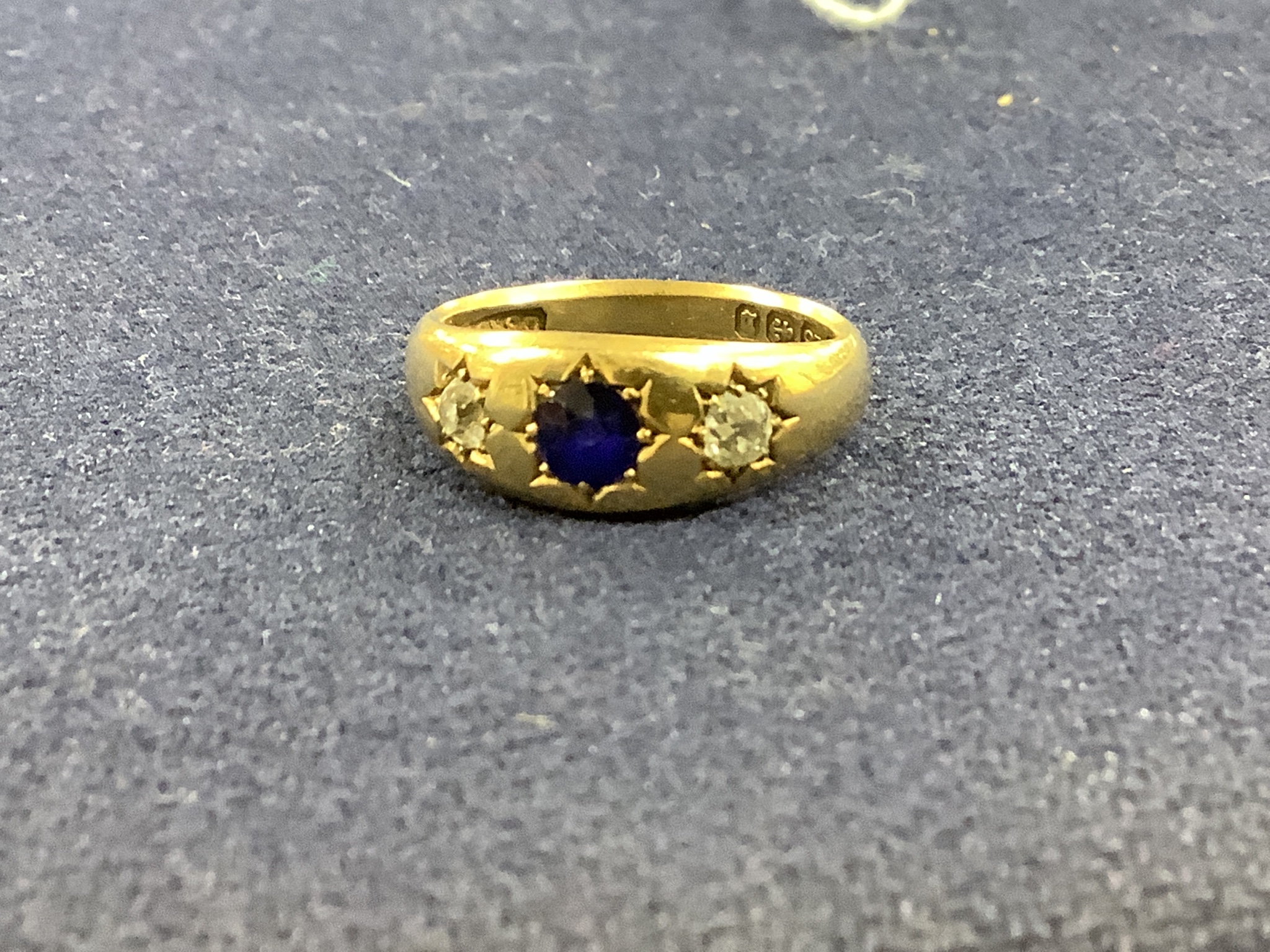 A late Victorian 18ct gold and gypsy set sapphire and diamond three stone ring, size N, gross 5.8 grams.